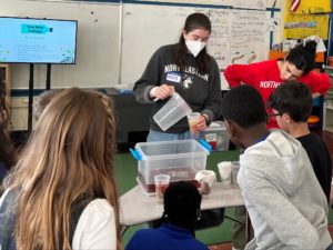 Northeastern volunteer pours polluted water into student made water filters